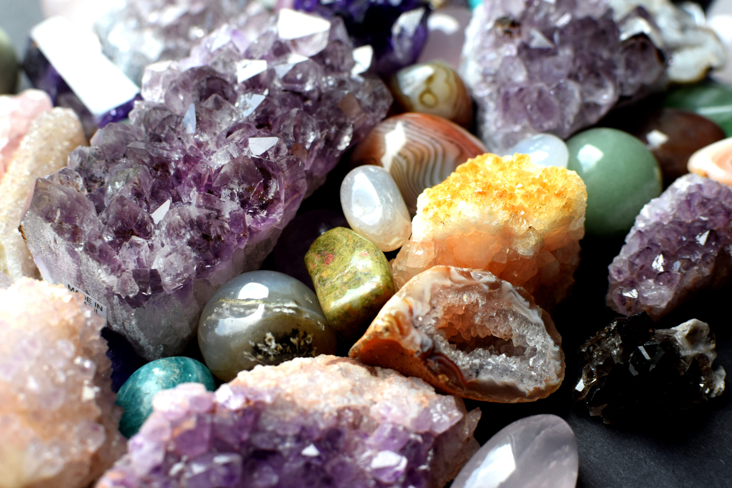 Background made of beautiful natural colored semi-precious stones. Close-up of amethyst, rose quartz and citrine crystals.